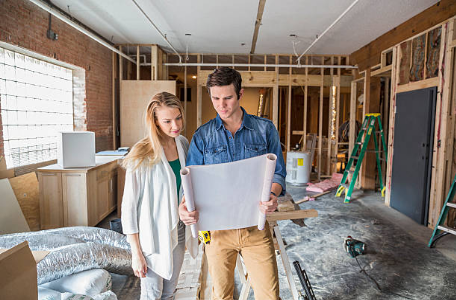 un homme et une femme regardant des plans dans une maison en construction