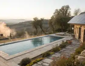 Une piscine extérieure chauffée par des panneaux solaires thermiques placés sur le toit ou à proximité, avec vapeur légère indiquant l'eau chauffée.